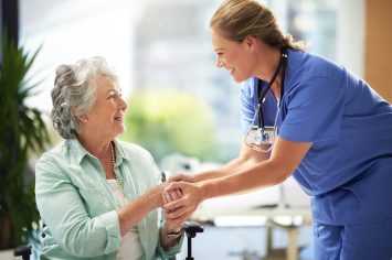 Shot of a doctor shaking hands with a smiling senior woman sitting in a wheelchair.