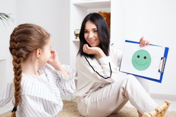 Therapist showing to the little patient smiling face on the paper. Psychologist consept